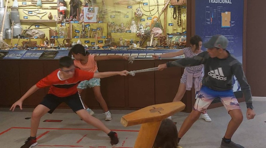 Dos parejas de niños del campamento alalá juegan a un juego tradicional en el museo melga