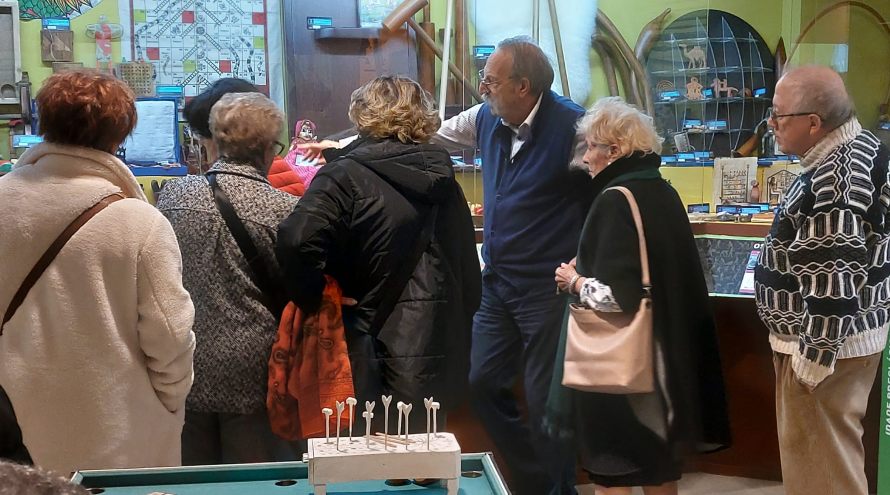 Ricardo Pérez y Verdez explica sinalando cara un expositor ao grupo do Fogar Parroquial de Santa María e Santiago da Coruña